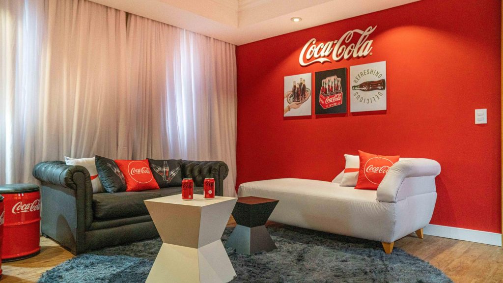 A sala é toda decorada com as cores e o logo da marca de refrigerantes. 