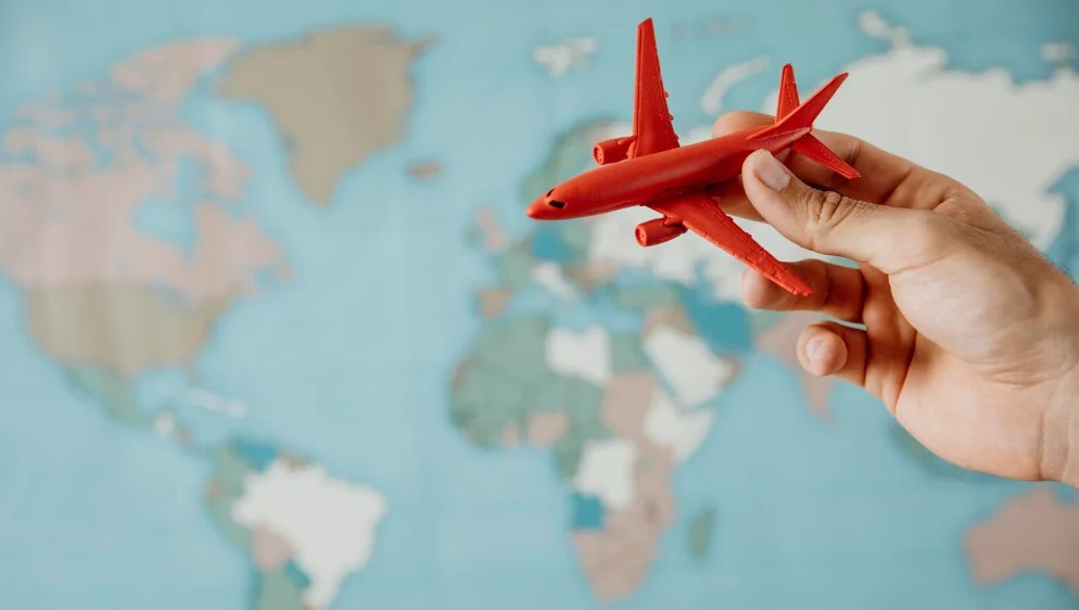 imagem ilustrativa de viagem internacional com aviao de brinquedo vermelho sobre mapa