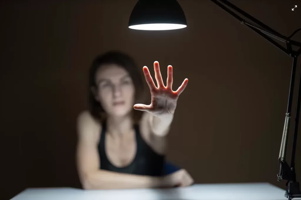 imagem ilustrativa de mulher com mão sob luz de lâmpada reflexão psicanálise
