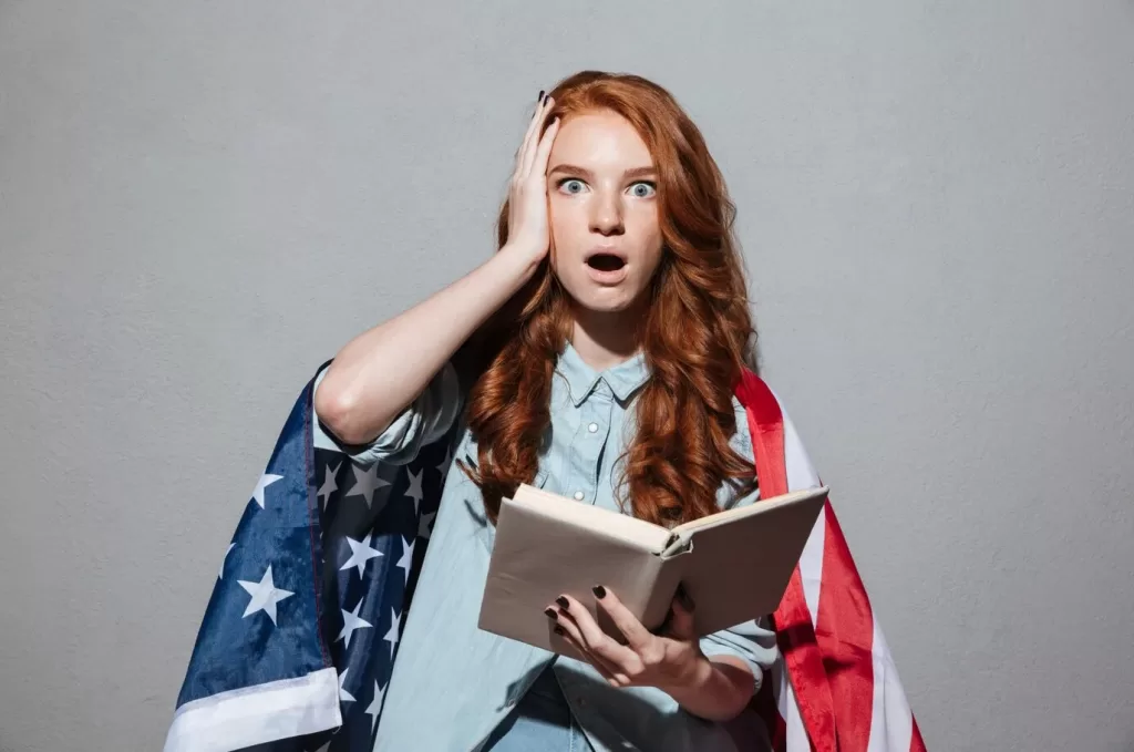 imagem ilustrativa inglês e cultura com estudante envolta em bandeira americana segurando livro