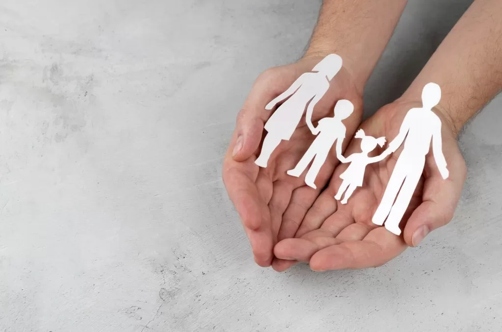 imagem ilustrativa da educação parental com mãos segurando figuras de família de papel